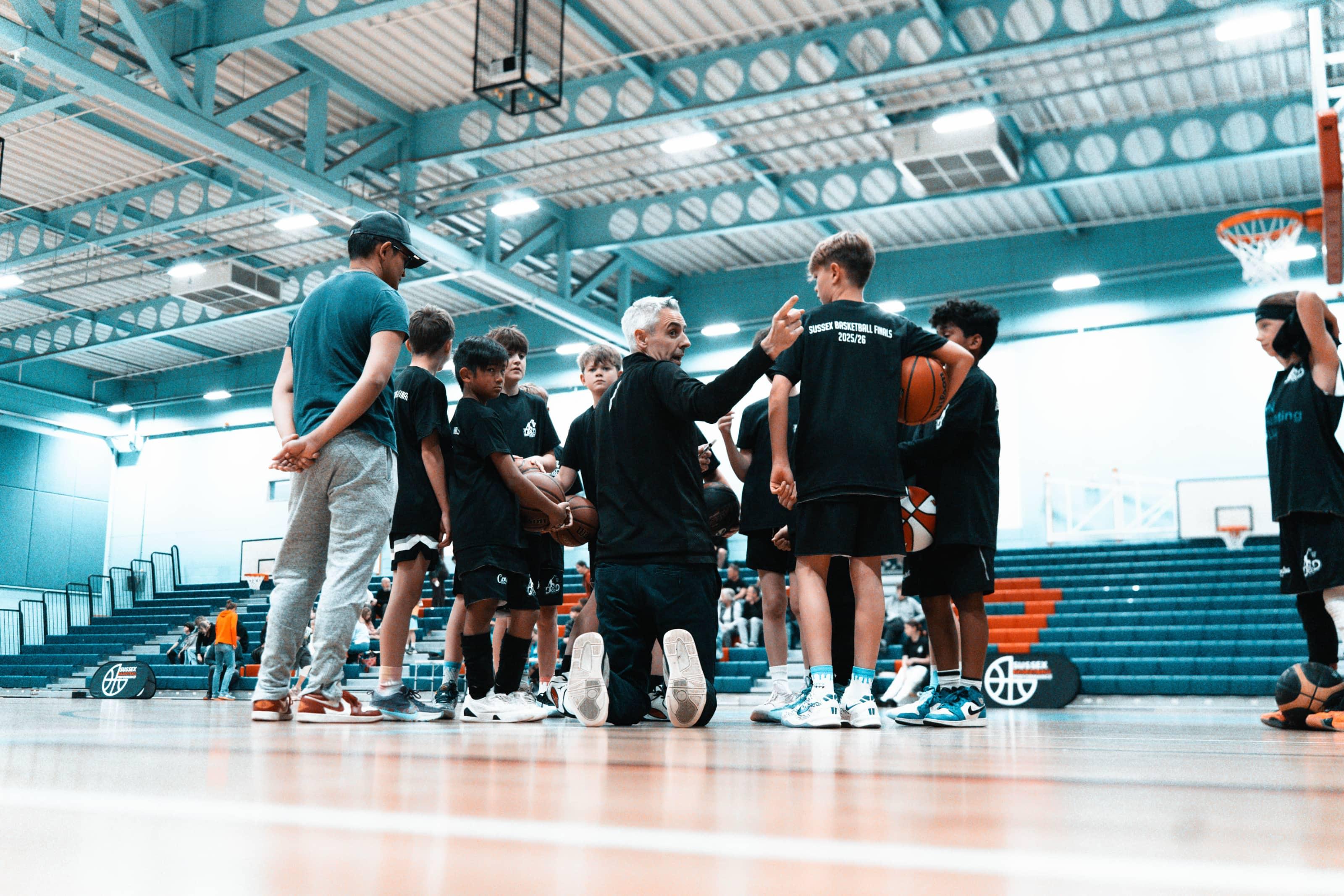 A D&D team and coach standing in a huddle with their arms around each other's shoulders