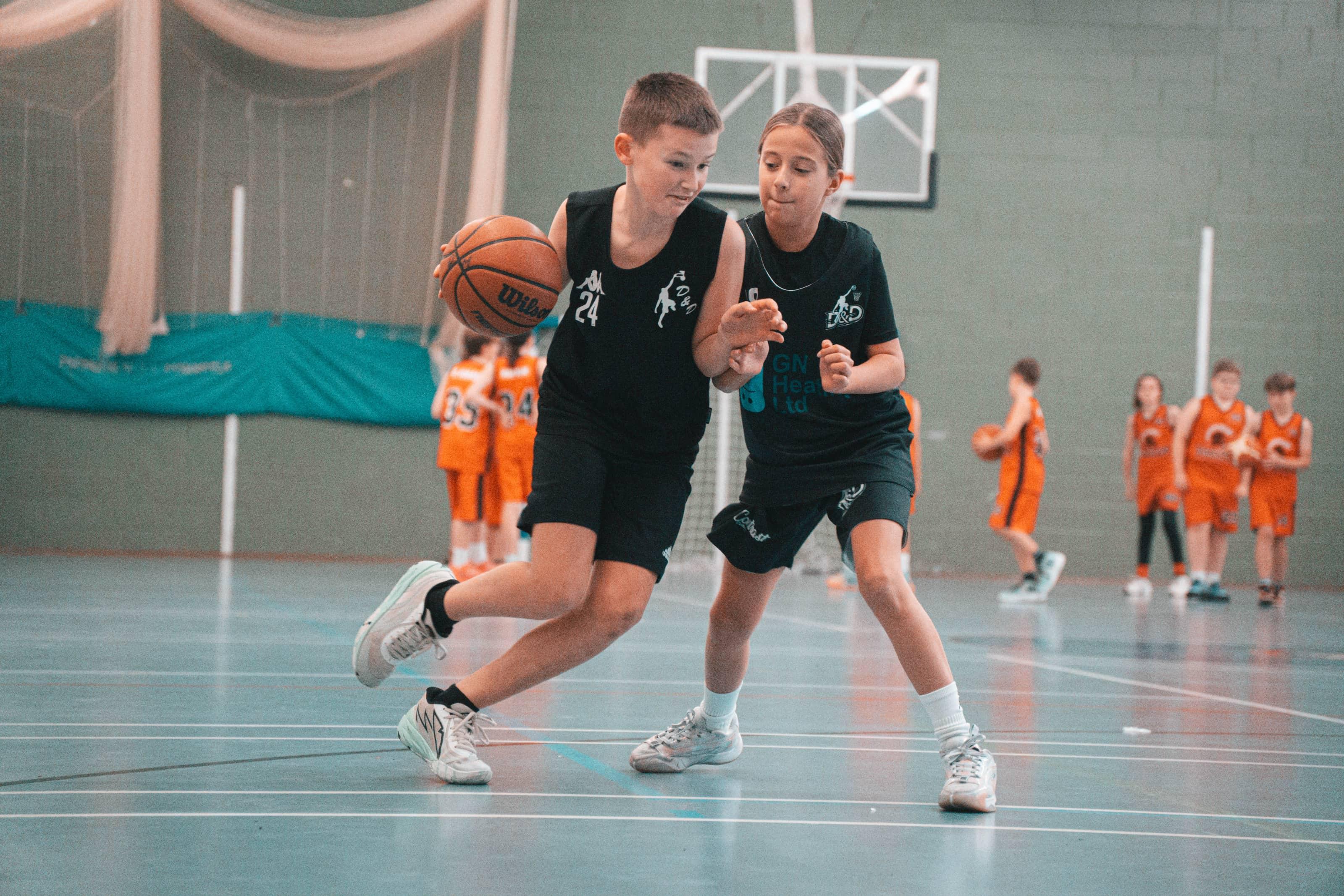 A basketball player wearing jersey number 24 driving with the ball while being closely defended